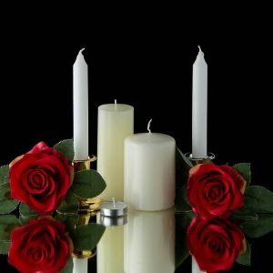 Front view white candles with red flowers black wall