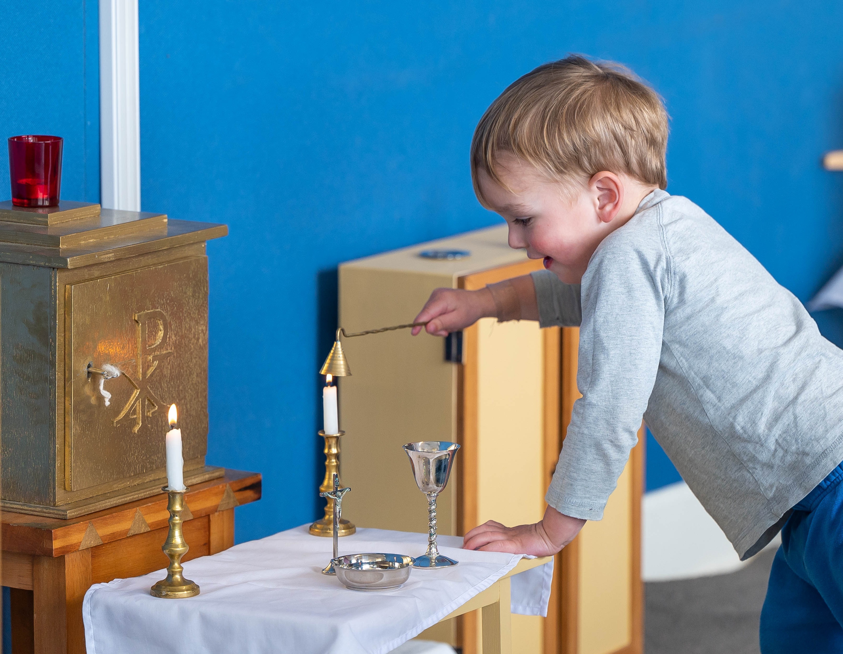 3 year old snuffing the altar candle
